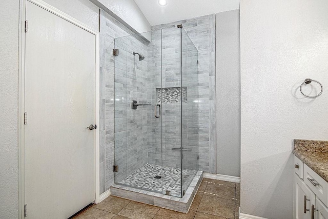 bathroom featuring tile patterned flooring, a shower stall, vanity, and baseboards