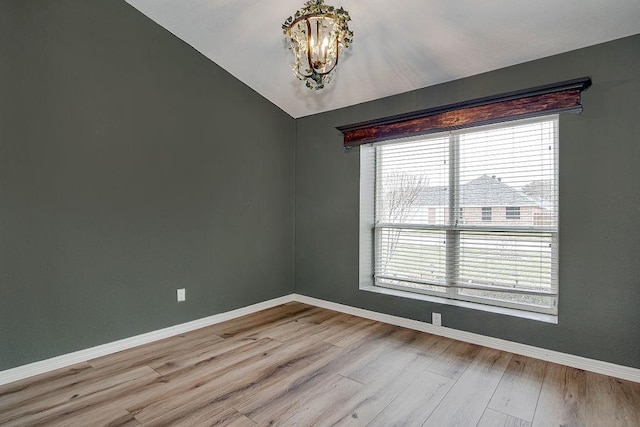 spare room featuring a chandelier, baseboards, wood finished floors, and vaulted ceiling