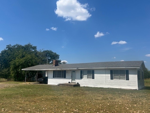 view of front of house with an attached carport, a front yard, and a chimney