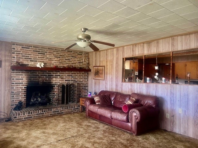 carpeted living room with a ceiling fan, a fireplace, and wood walls