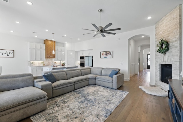 living room with recessed lighting, a fireplace, arched walkways, ceiling fan, and hardwood / wood-style flooring