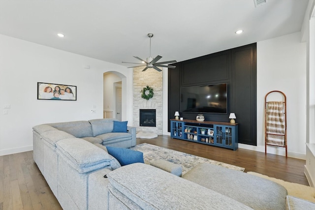 living room with baseboards, recessed lighting, a fireplace, wood finished floors, and a ceiling fan