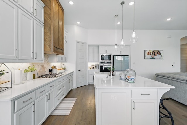 kitchen with backsplash, dark wood-style floors, stainless steel appliances, arched walkways, and light countertops