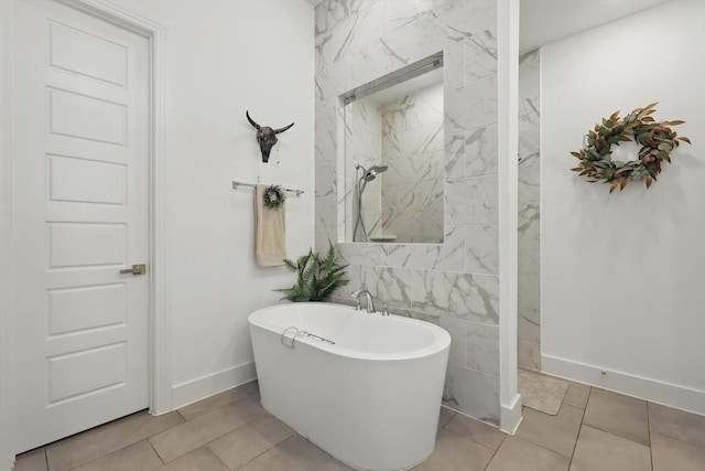 bathroom featuring tile patterned flooring, tiled shower, baseboards, and a freestanding tub