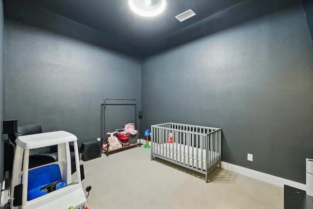 carpeted bedroom featuring a nursery area, baseboards, visible vents, and a textured wall