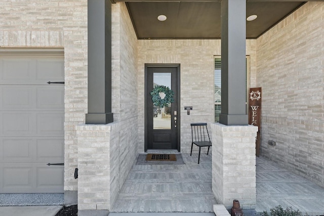 view of exterior entry with brick siding and an attached garage