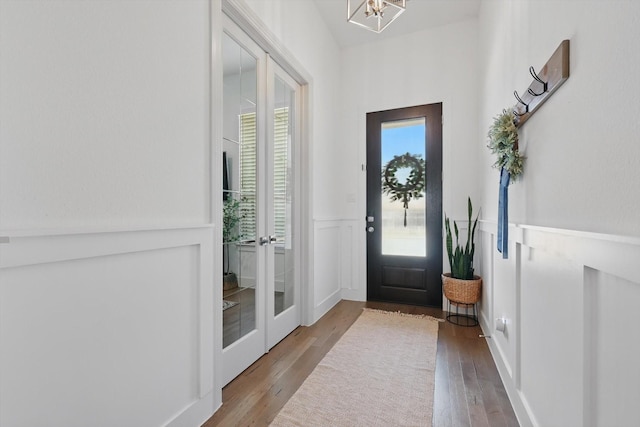 foyer featuring a decorative wall, wood finished floors, and a wainscoted wall