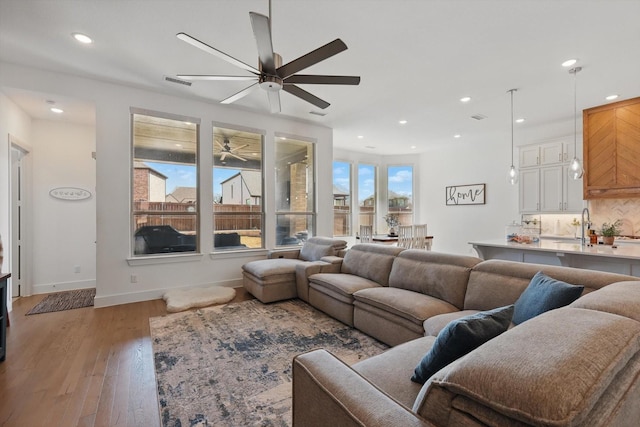 living room featuring baseboards, visible vents, recessed lighting, ceiling fan, and light wood-type flooring