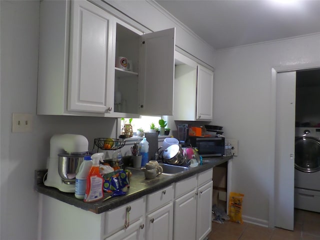 kitchen with dark countertops, washer / clothes dryer, white cabinetry, and black microwave