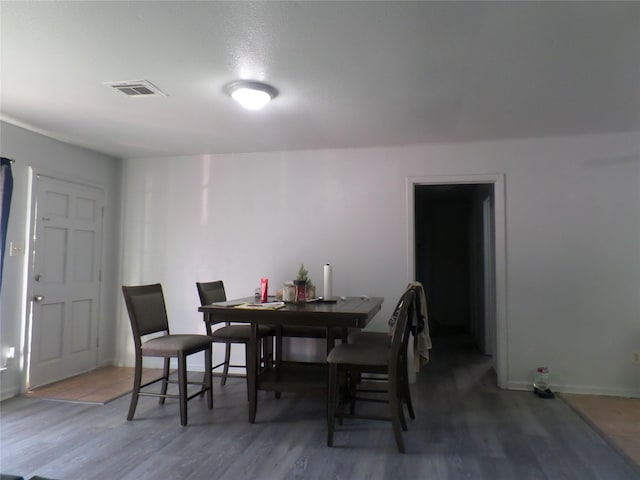 dining space with visible vents, baseboards, and wood finished floors