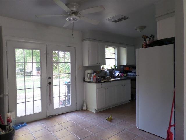 kitchen featuring dark countertops, visible vents, light tile patterned floors, freestanding refrigerator, and stove