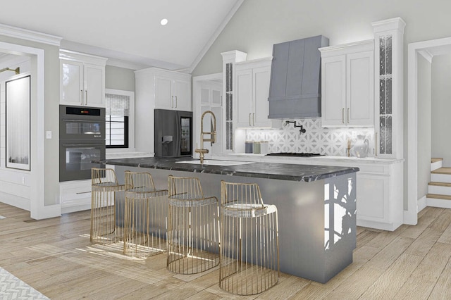 kitchen featuring double oven, light wood-type flooring, custom exhaust hood, white cabinetry, and a sink