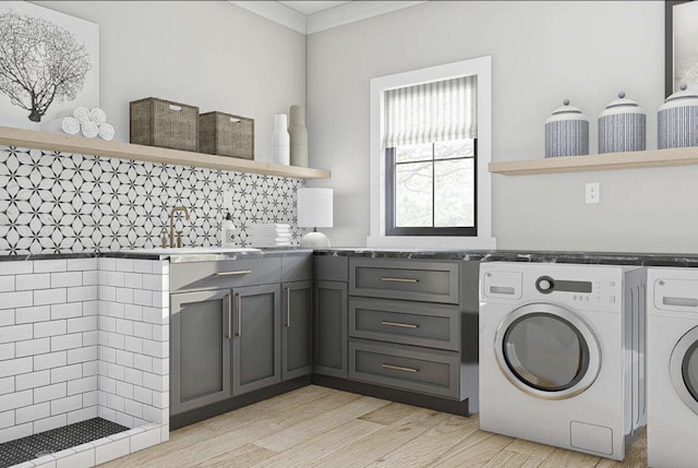 laundry room with ornamental molding, a sink, cabinet space, light wood-style floors, and washing machine and clothes dryer