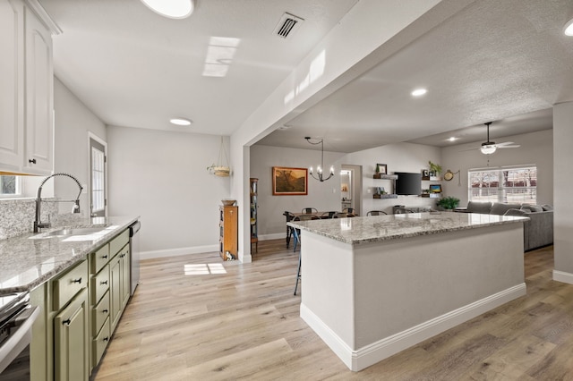 kitchen featuring light wood finished floors, a sink, baseboards, visible vents, and green cabinets
