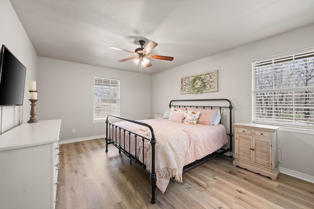 bedroom with ceiling fan, baseboards, and light wood finished floors