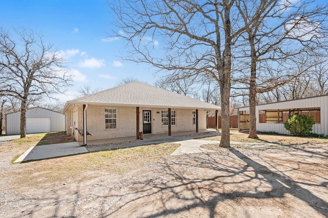 view of front of property with a shingled roof, an outdoor structure, a detached garage, a porch, and brick siding
