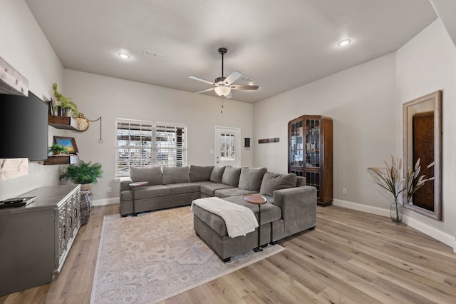 living area with light wood-style floors, ceiling fan, baseboards, and visible vents