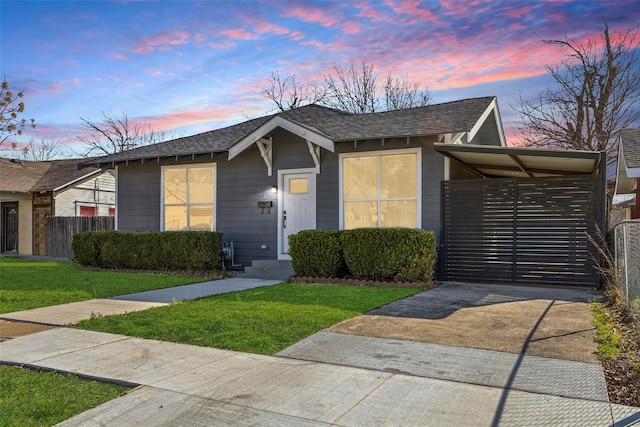 view of front of home featuring a front lawn, fence, driveway, and a shingled roof