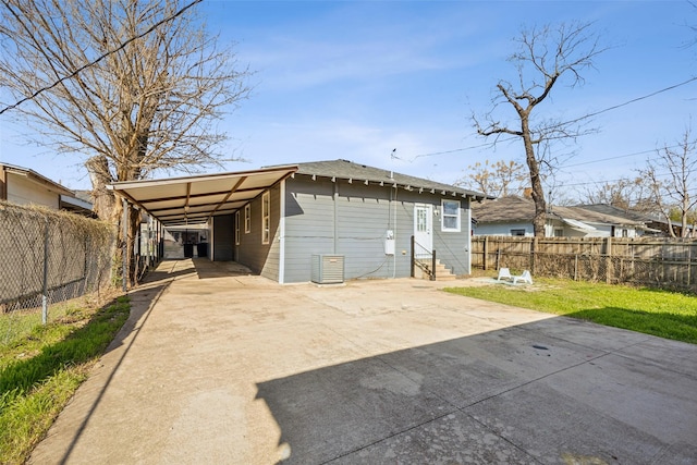 rear view of house featuring an attached carport, fence, entry steps, a lawn, and driveway