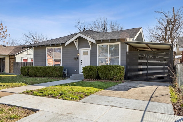 view of front of home with driveway, a shingled roof, a front yard, and fence