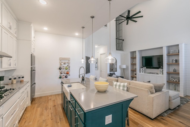 kitchen featuring white cabinetry, open floor plan, a kitchen island with sink, and stainless steel gas cooktop