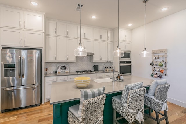 kitchen featuring visible vents, light wood-style flooring, backsplash, white cabinetry, and appliances with stainless steel finishes