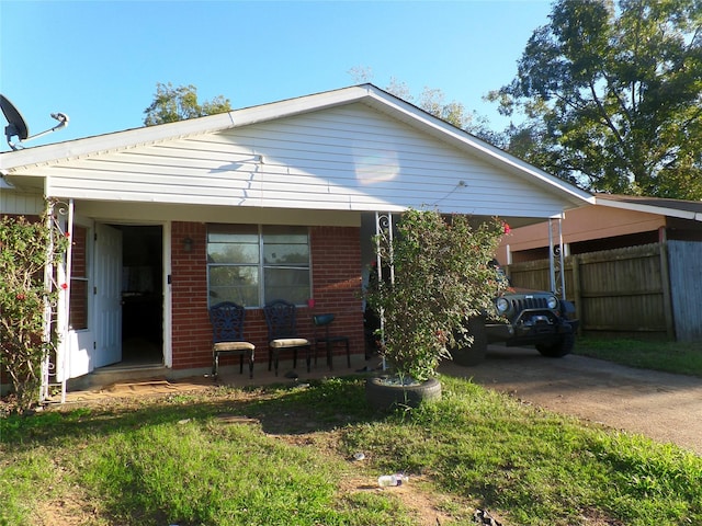 view of front of home featuring brick siding, covered porch, concrete driveway, and fence