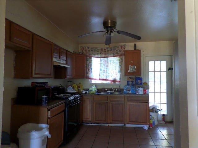 kitchen featuring a ceiling fan, light tile patterned flooring, a sink, black gas range, and under cabinet range hood