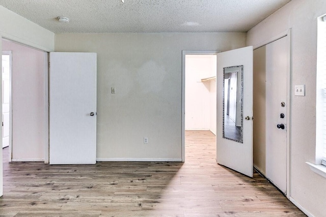 foyer entrance featuring a textured ceiling, baseboards, and wood finished floors