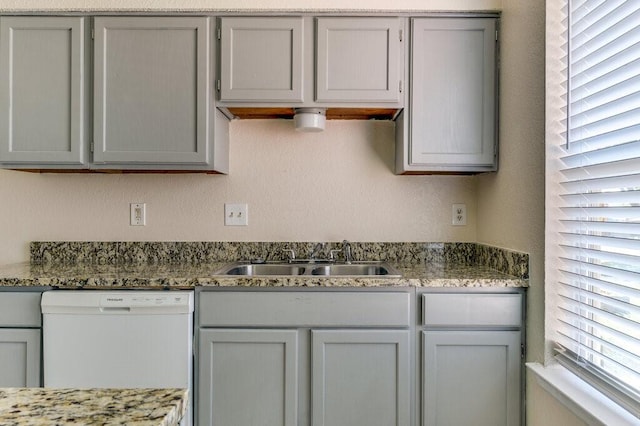 kitchen with gray cabinetry, white dishwasher, and a sink