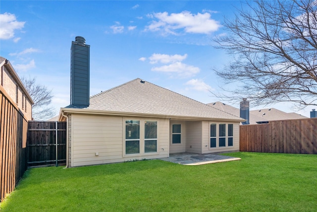 rear view of house with roof with shingles, a yard, a fenced backyard, a chimney, and a patio area