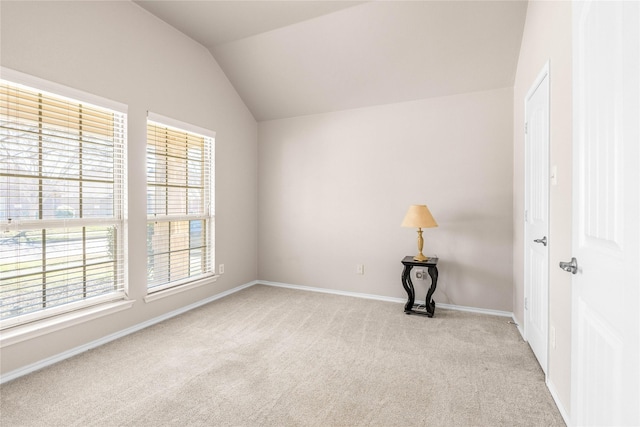 unfurnished room with lofted ceiling, baseboards, and light carpet