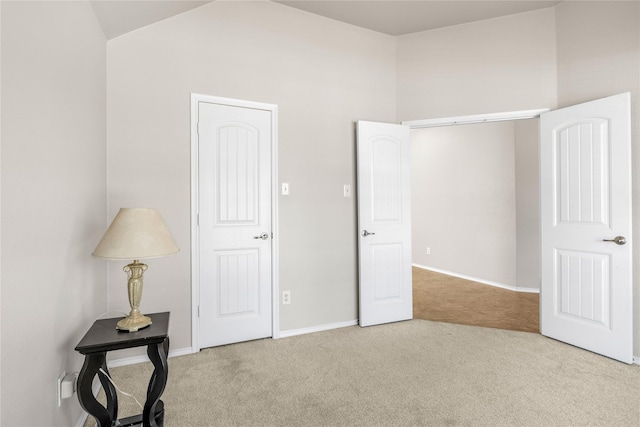 unfurnished bedroom with carpet flooring, baseboards, and lofted ceiling