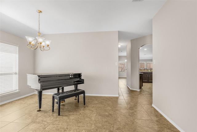 sitting room with light tile patterned floors, arched walkways, baseboards, and a chandelier