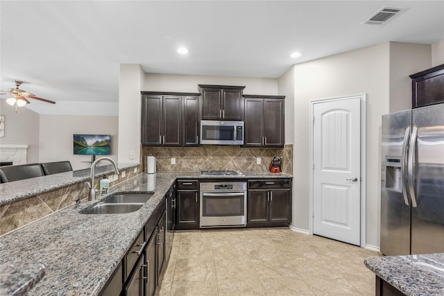 kitchen with visible vents, a sink, light stone counters, tasteful backsplash, and stainless steel appliances