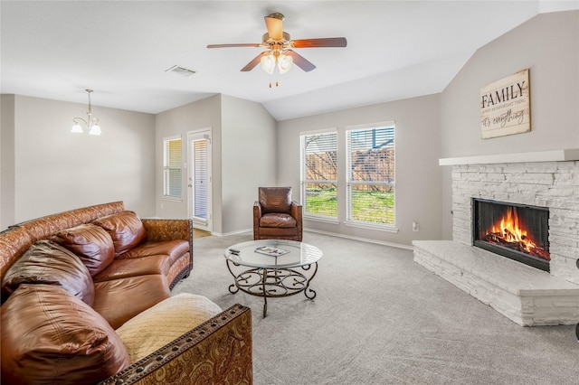 carpeted living area featuring visible vents, lofted ceiling, ceiling fan with notable chandelier, a stone fireplace, and baseboards