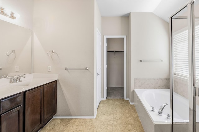 bathroom with a spacious closet, baseboards, lofted ceiling, a bath, and vanity