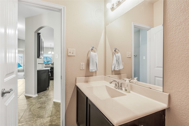 bathroom with vanity, a textured wall, and tile patterned flooring