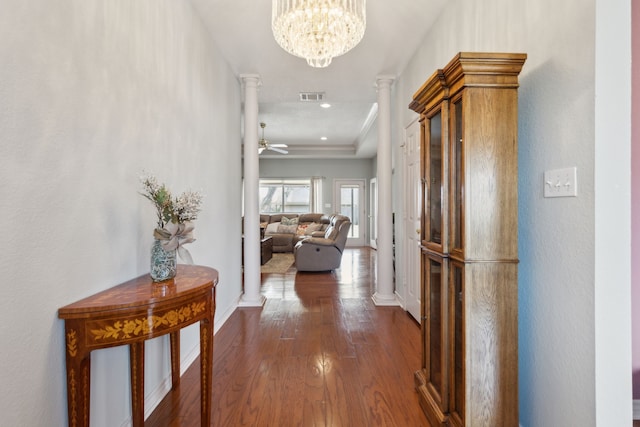 hall with visible vents, dark wood finished floors, an inviting chandelier, decorative columns, and baseboards