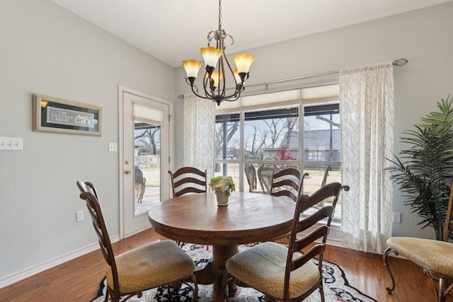 dining area with baseboards, an inviting chandelier, and wood finished floors