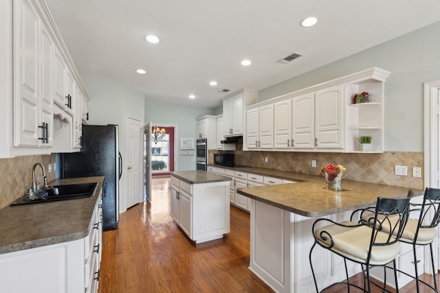 kitchen with dark wood-style floors, open shelves, a sink, white cabinets, and dark countertops