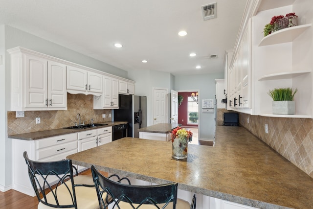 kitchen with visible vents, open shelves, a breakfast bar area, white cabinetry, and a sink