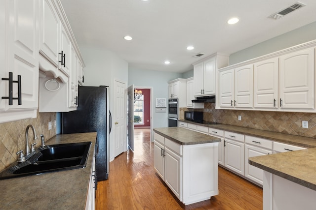 kitchen with light wood-style floors, visible vents, under cabinet range hood, and a sink