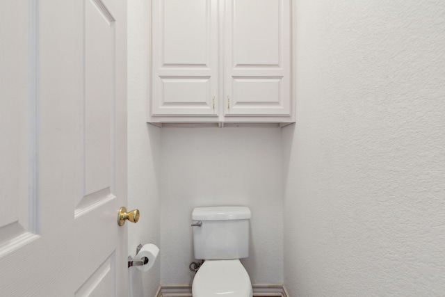 bathroom with toilet and a textured wall