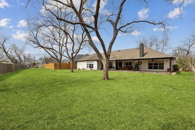 rear view of house featuring a yard, a chimney, ceiling fan, and fence