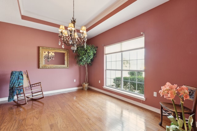 sitting room with a notable chandelier, a raised ceiling, baseboards, and wood finished floors