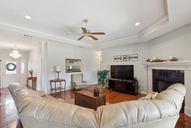 living area featuring visible vents, a tray ceiling, wood finished floors, baseboards, and a tile fireplace