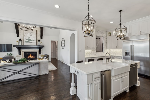 kitchen with backsplash, open floor plan, built in fridge, white cabinets, and a sink