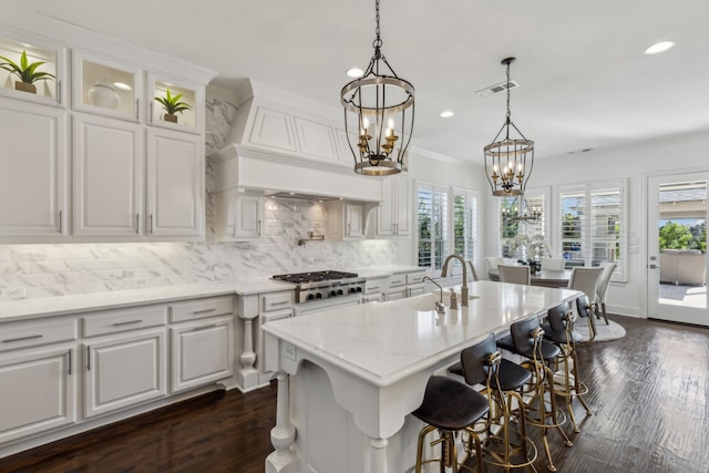 kitchen with visible vents, a sink, tasteful backsplash, custom exhaust hood, and stainless steel gas cooktop