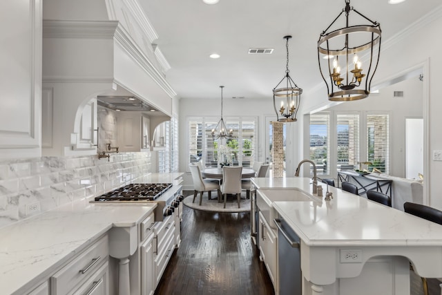 kitchen featuring visible vents, a sink, tasteful backsplash, stainless steel appliances, and an inviting chandelier